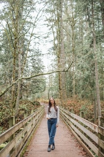Bridge_Full Length_services page Large Breanna Owen, Licensed and Certified Mental Health Counselor on a wooden walkway in the woods.